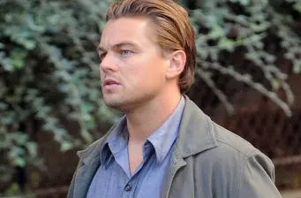 Leonardo DiCaprio in jacket looks sideways in outdoor movie still