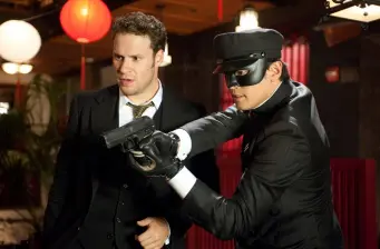 man in mask points gun while another man looks on in tense scene