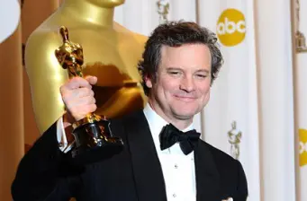 Colin Firth holding an Oscar trophy in tuxedo at awards