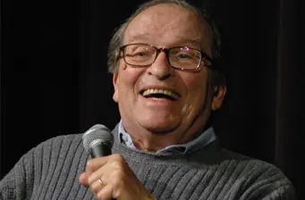 Director Sidney Lumet smiles speaking into microphone at event