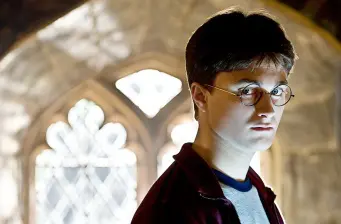 Harry Potter character wearing glasses looks serious in moody lighting