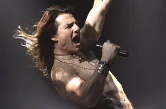Tom Cruise shirtless singing passionately with microphone in hand