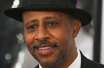 Close-up headshot of a smiling man wearing a black hat