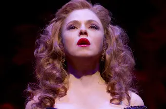 Close-up of woman with curly hair and red lipstick on stage