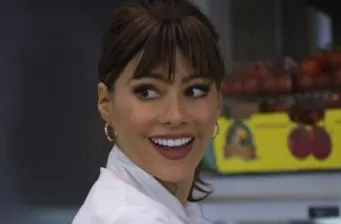 Woman with brown hair and hoop earrings smiling, indoor setting