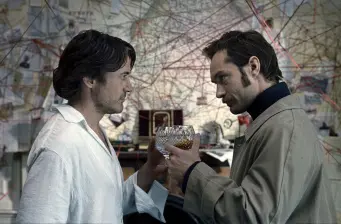 two men clinking glasses in front of evidence wall