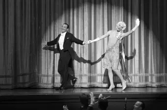 man and woman on stage holding hands in spotlight during performance