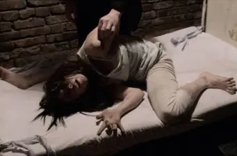 Woman in white clothes lying distressed on bed in dark room