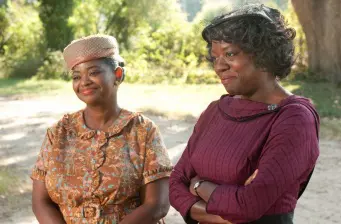 Two women in 1960s attire smiling outdoors in The Help movie still