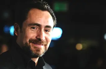 Close-up of man with beard smiling in dim lighting