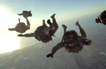 four military soldiers in tactical gear parachuting in formation