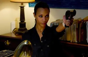 Zoe Saldana aiming a gun in an intense scene indoors