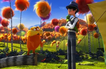 The Lorax and a boy in a bright animated forest with Truffula trees