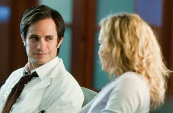 Gael García Bernal in white coat talks to blonde woman in scene