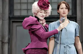 Elizabeth Banks as Effie with Jennifer Lawrence as Katniss holding microphone