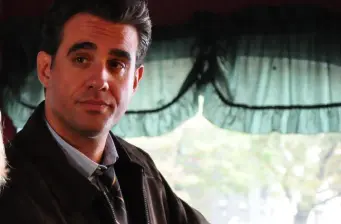 Bobby Cannavale in a headshot wearing jacket and tie indoors