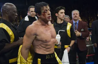 Sylvester Stallone as bruised boxer with team in ring