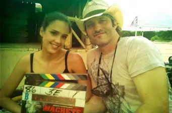 Man in cowboy hat and woman hold clapperboard on film set