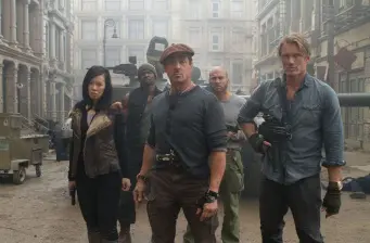 Four armed people stand alert on a foggy city street