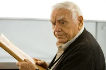 Ernest Borgnine reading a document indoors, wearing dark sweater