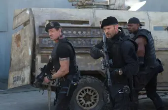Three armed men in tactical gear near military vehicle