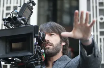 Man adjusts focus on professional video camera, hand raised