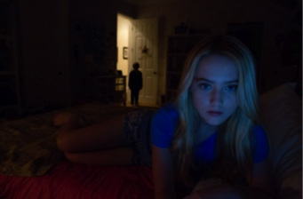 young woman on bed with shadowy child figure in doorway behind her