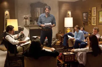 Group of men in living room reading papers, discussing strategy