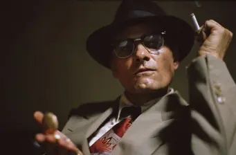 Man in suit and hat smoking cigarette in tense scene