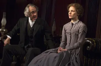 Two actors in period costume seated talking in a Broadway scene