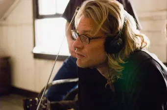 Director Andrew Dominik wearing headphones and glasses in indoor setting