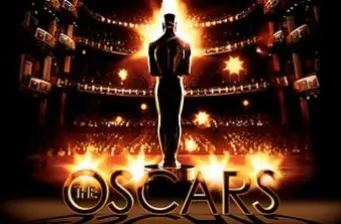 Oscar statuette silhouette and The Oscars logo glowing over audience