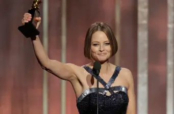 Jodie Foster raises Golden Globe award while speaking at microphone
