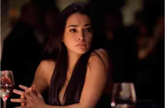 Natalie Martinez sitting clasping hands, looking to side in dim lighting