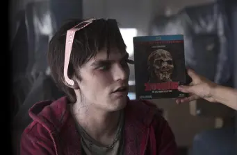 man in hoodie watches zombie movie DVD cover near face