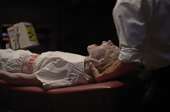 man lying on table with another person holding his head tightly