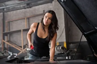 Michelle Rodriguez in black tank top working under a car hood