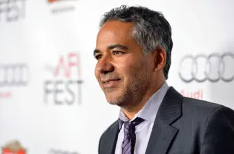 John Ortiz in suit smiling by AFI FEST backdrop
