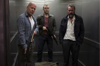 three armed men stand tense inside an elevator