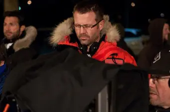 man in red parka jacket working with equipment outdoors at night