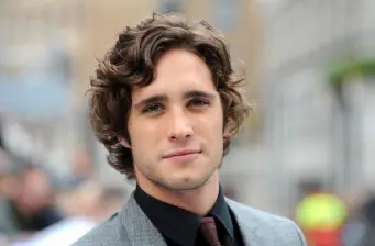 Diego Boneta portrait wearing black shirt and tie outdoors