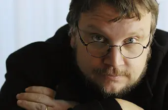 Guillermo Del Toro headshot wearing glasses, looking at camera