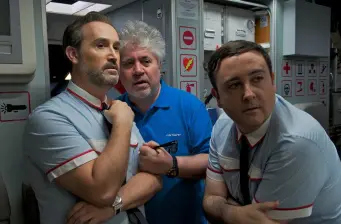 Three men in airplane cabin, two wearing flight attendant uniforms
