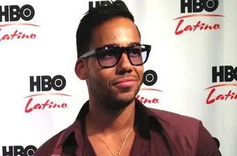 Romeo Santos at HBO Latino event wearing glasses and maroon shirt