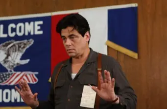 Benicio del Toro gestures with hands raised in movie scene