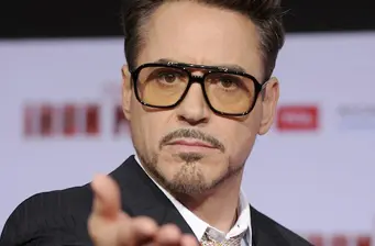 Robert Downey Jr. points while wearing tinted glasses in close-up