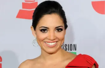 Woman in red dress smiling in front of event backdrop