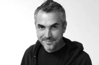 Headshot of Mexican director Alfonso Cuarón smiling in black and white