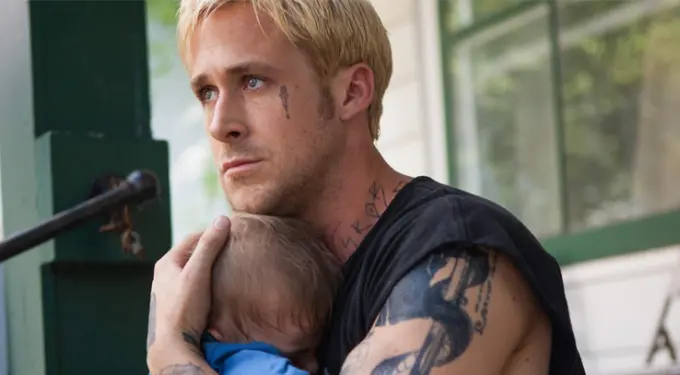 tattooed man holding child tightly, looking serious outside