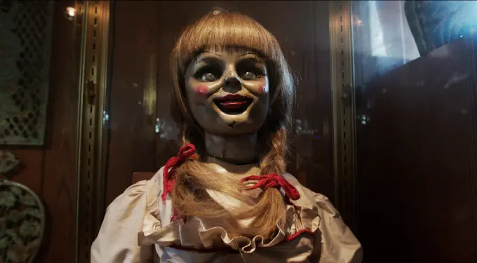 Close-up of Annie doll with braided hair and cracked face in display case